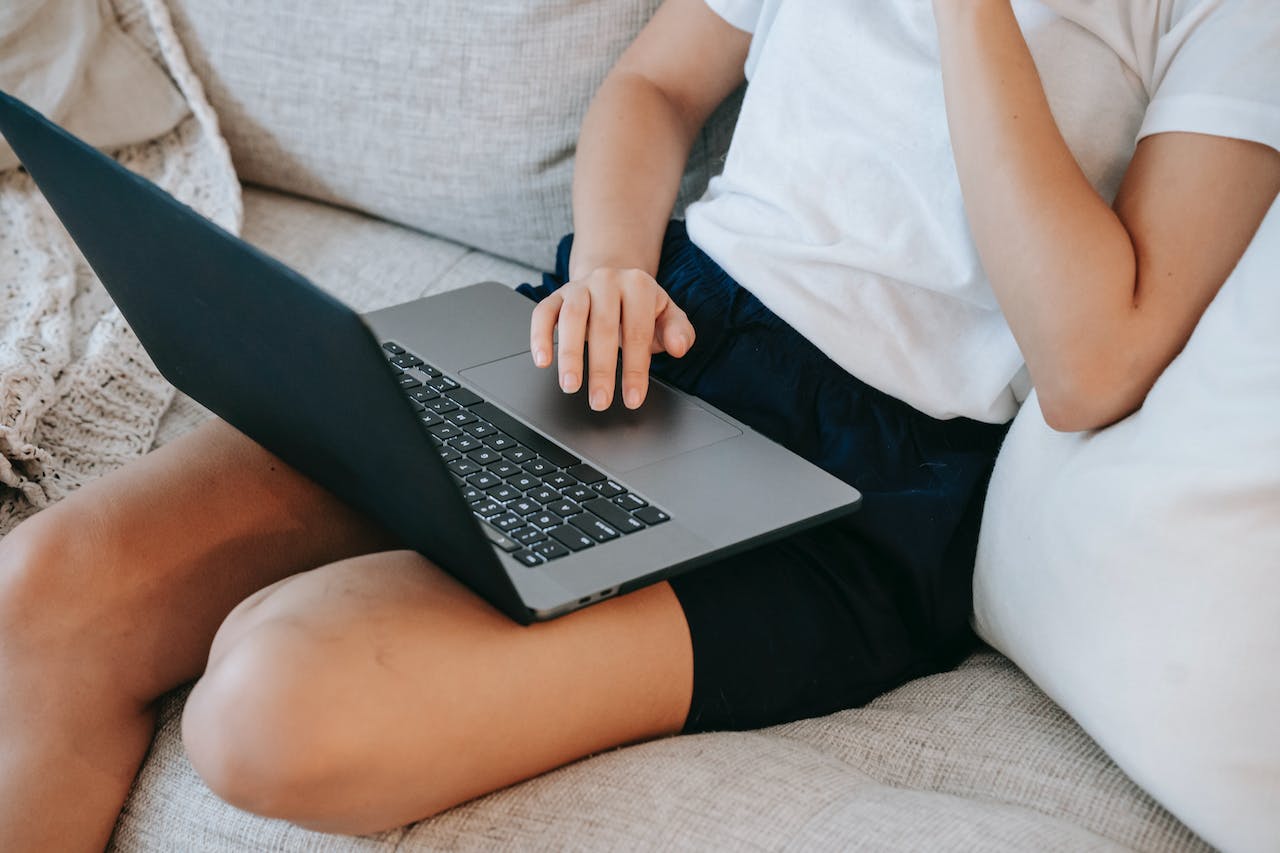 Anonymous Female Freelancer Working Remotely on Laptop on Sofa