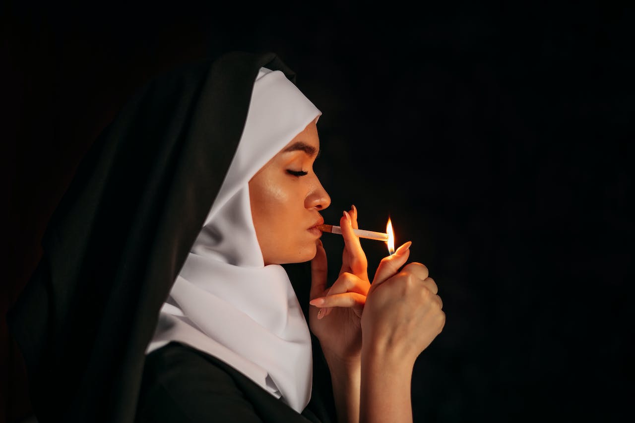 A Woman with Black and White Head Scarf Lighting Up a Cigarette