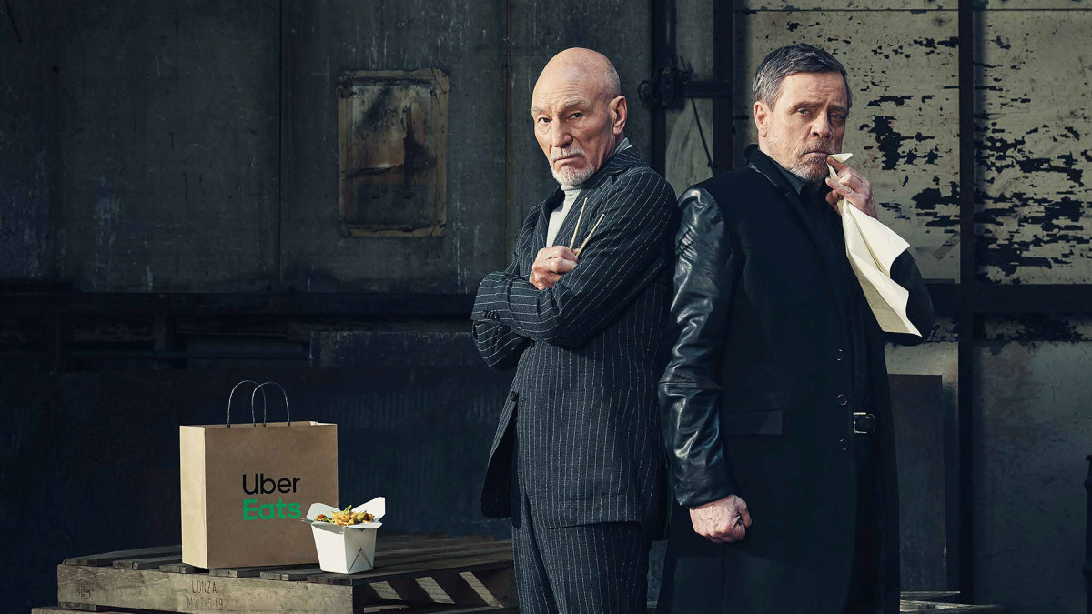 Patrick Stewart and Mark Hamill stand side by side in a spacious warehouse