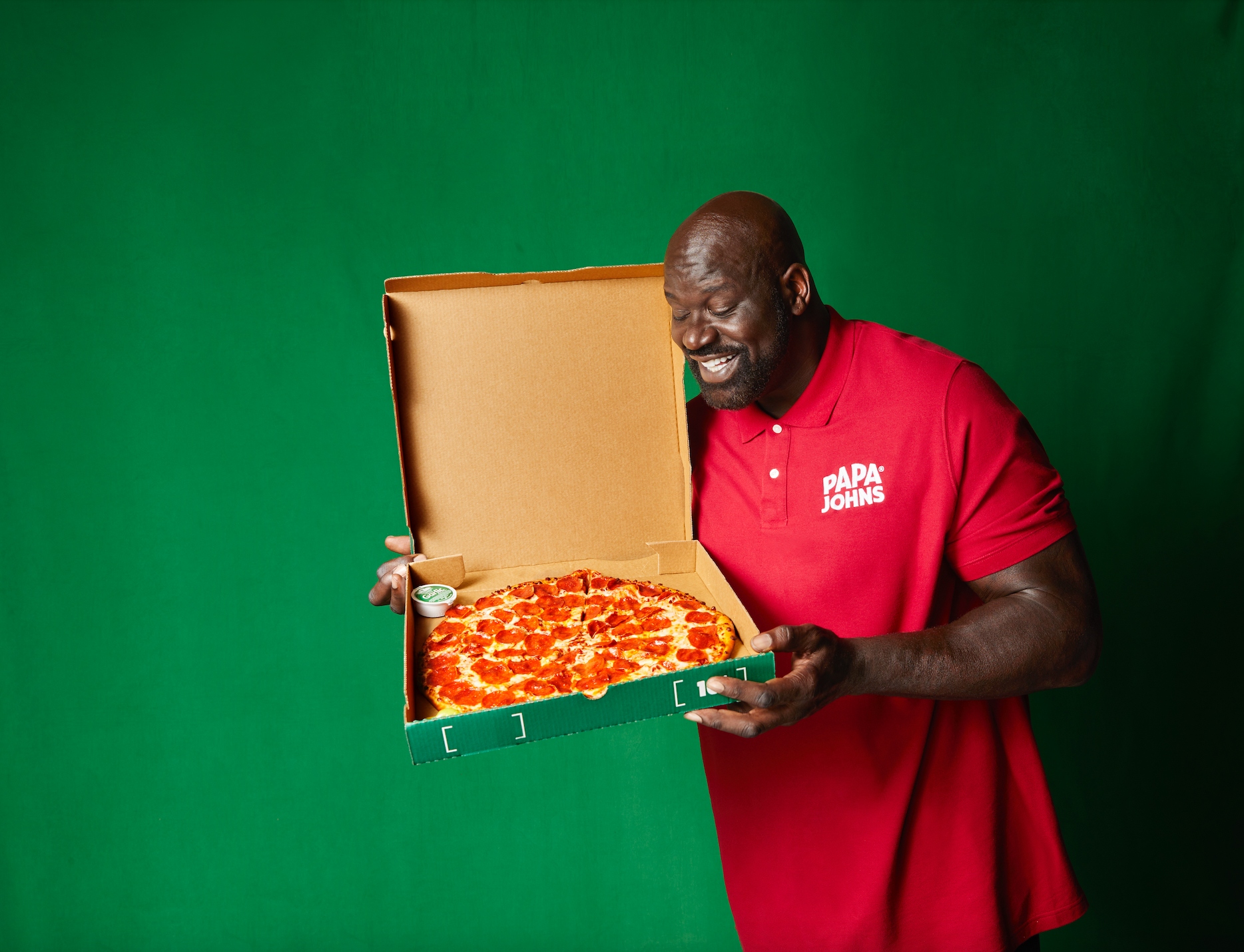 Shaquille O'Neal on a red shirt holding a box of pizza